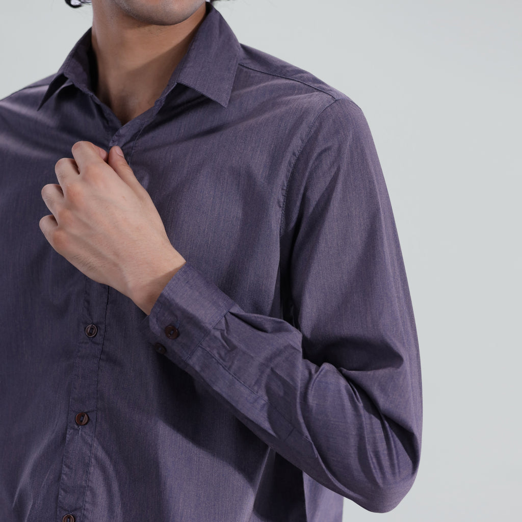 Man wearing a purple shirt with rolled-up sleeves on a gray background